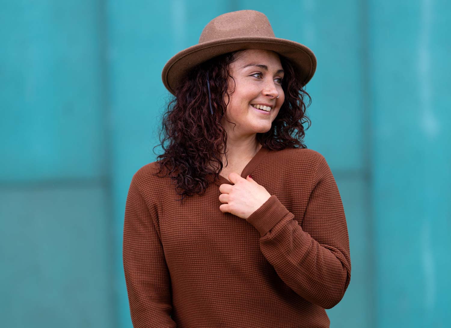 Personal branding portrait against a teal wall in natural light
